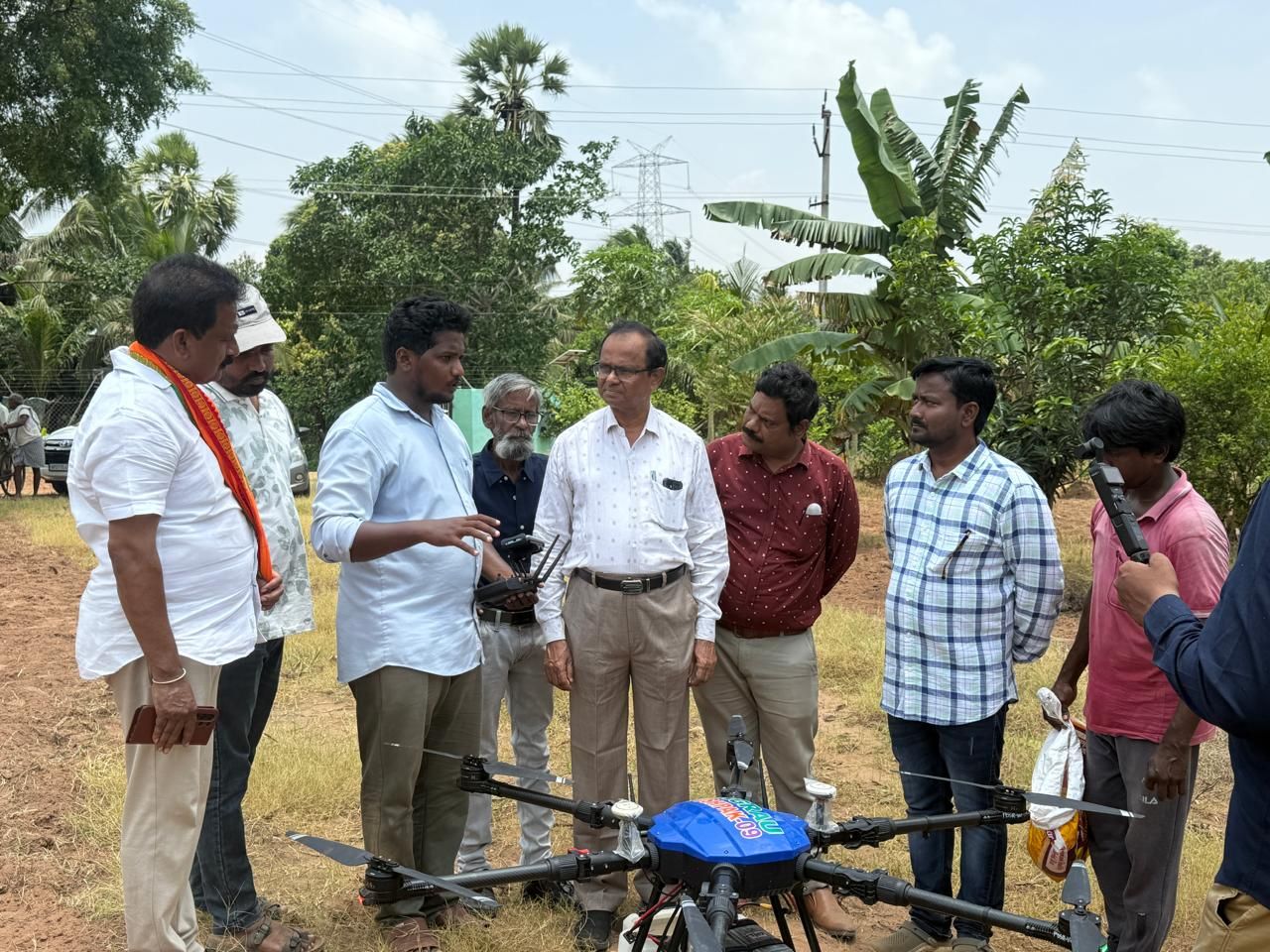 Farmers and officials gathered around an agricultural drone during a demonstration