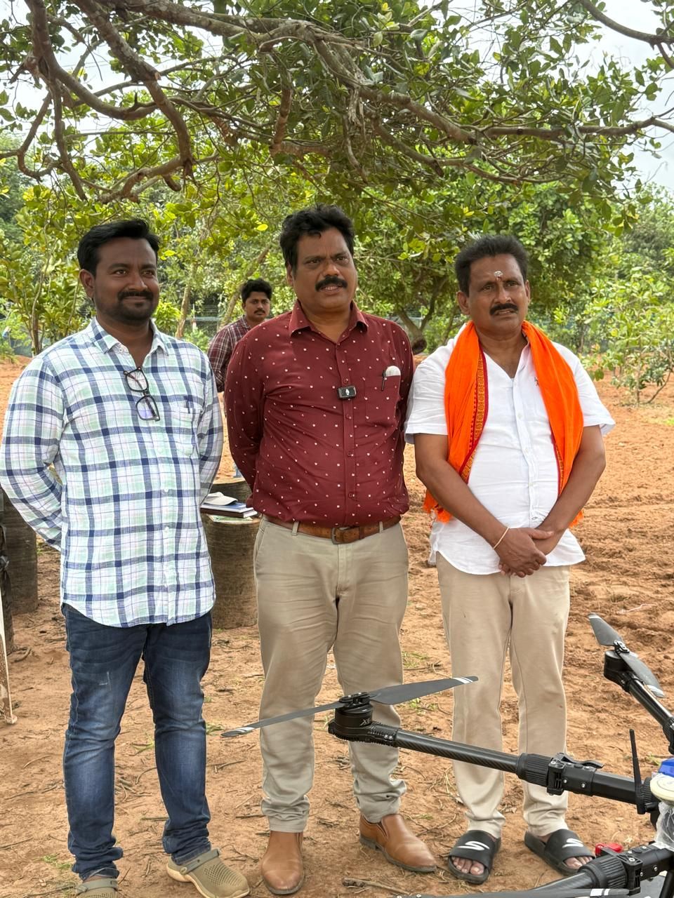 Three men standing beside an agricultural drone at the farm