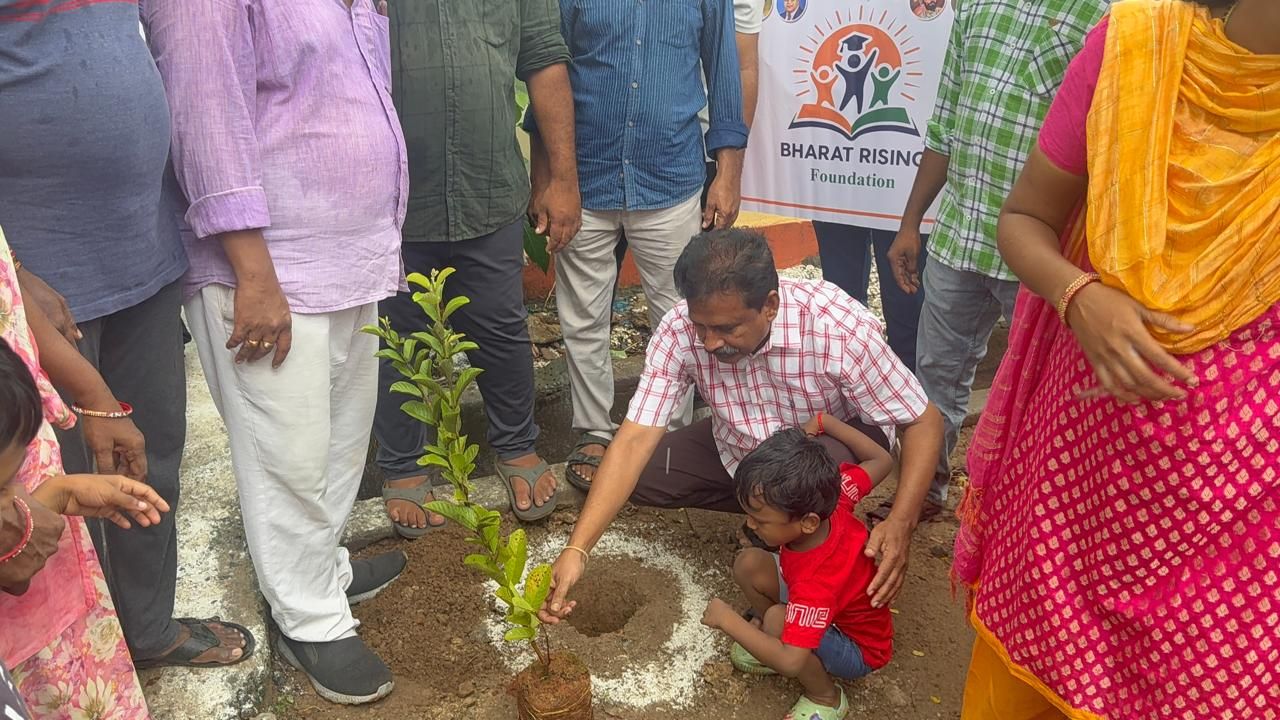 Volunteers and neighbours planting a sapling on a street, with a Bharat Rising Foundation banner behind